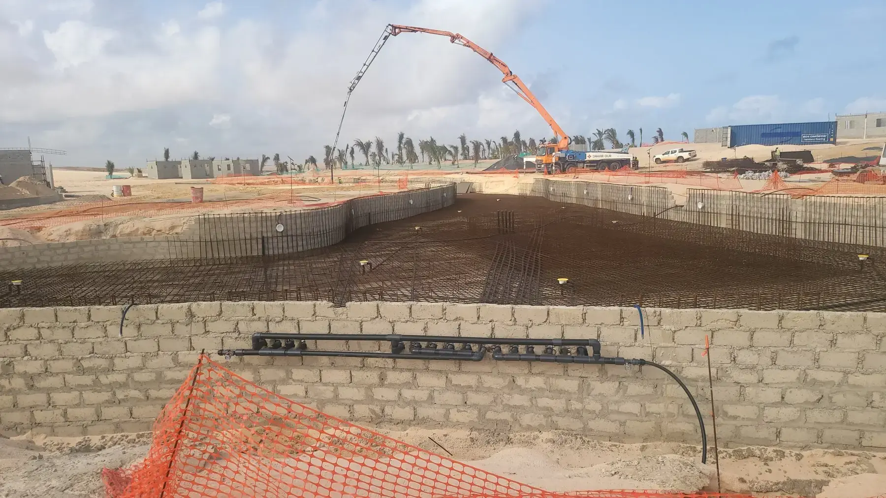 Chantier de bassin en béton armé : ferraillage du radier et pompe à béton