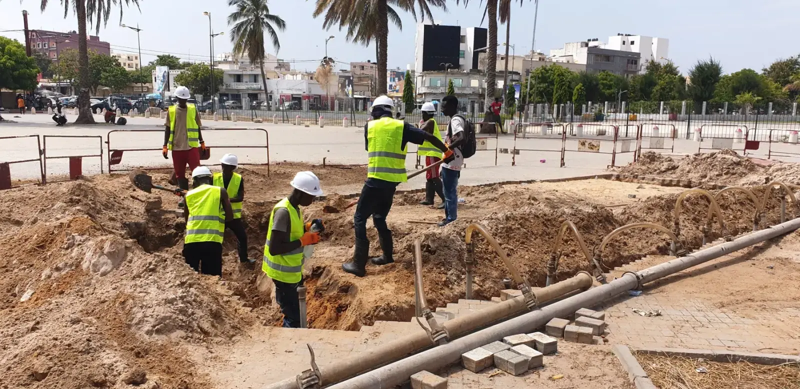 Équipe en gilets jaunes creusant une fouille pour la pose de conduites en milieu urbain